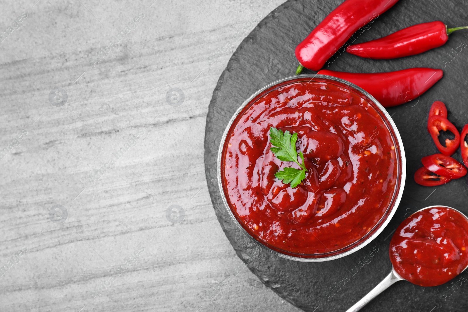 Photo of Flat lay composition with hot chili sauce on grey background. Space for text