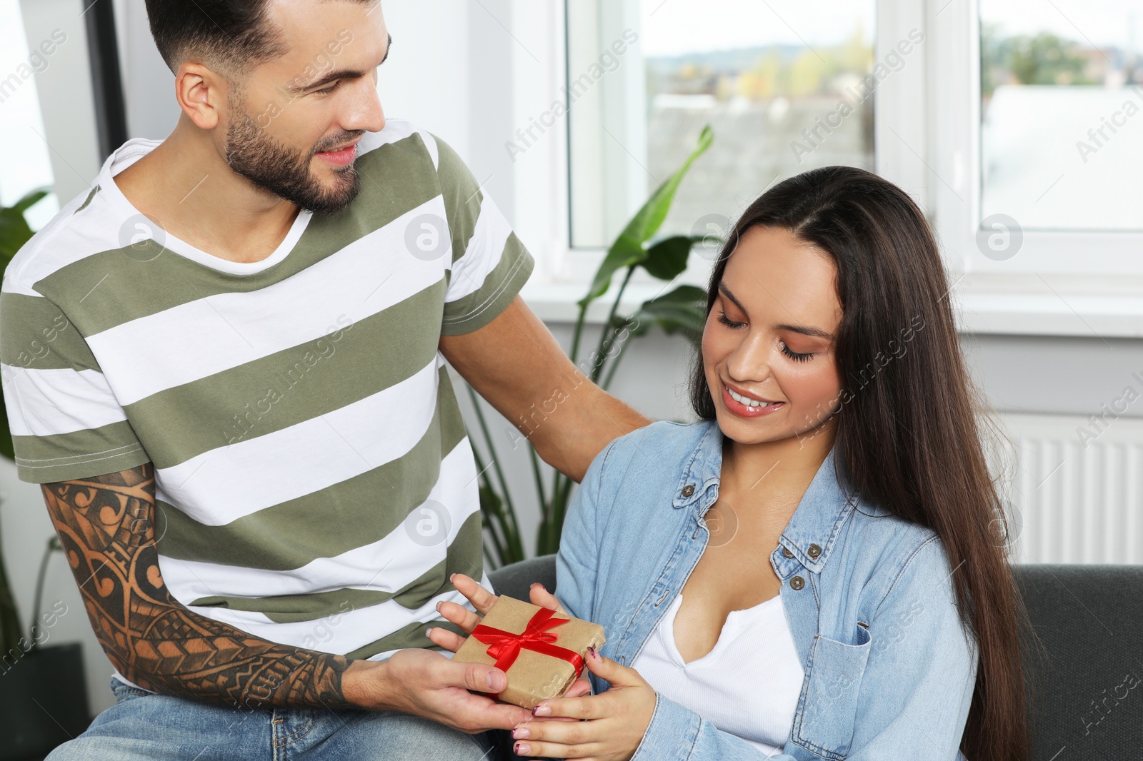 Photo of Man presenting gift to his girlfriend at home