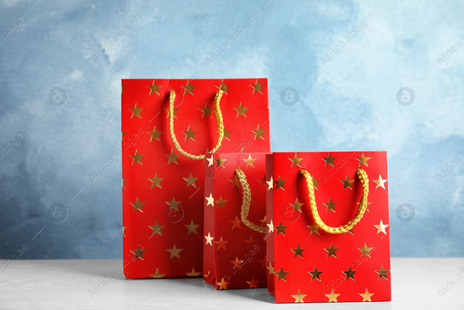 Photo of Red shopping paper bags with star pattern on white table