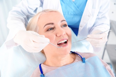 Photo of Dentist examining patient's teeth in modern clinic