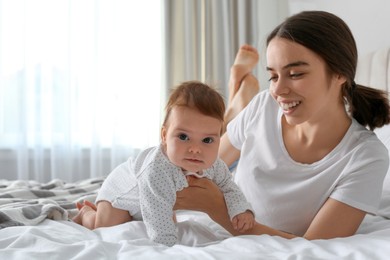 Photo of Young woman with her little baby on bed at home
