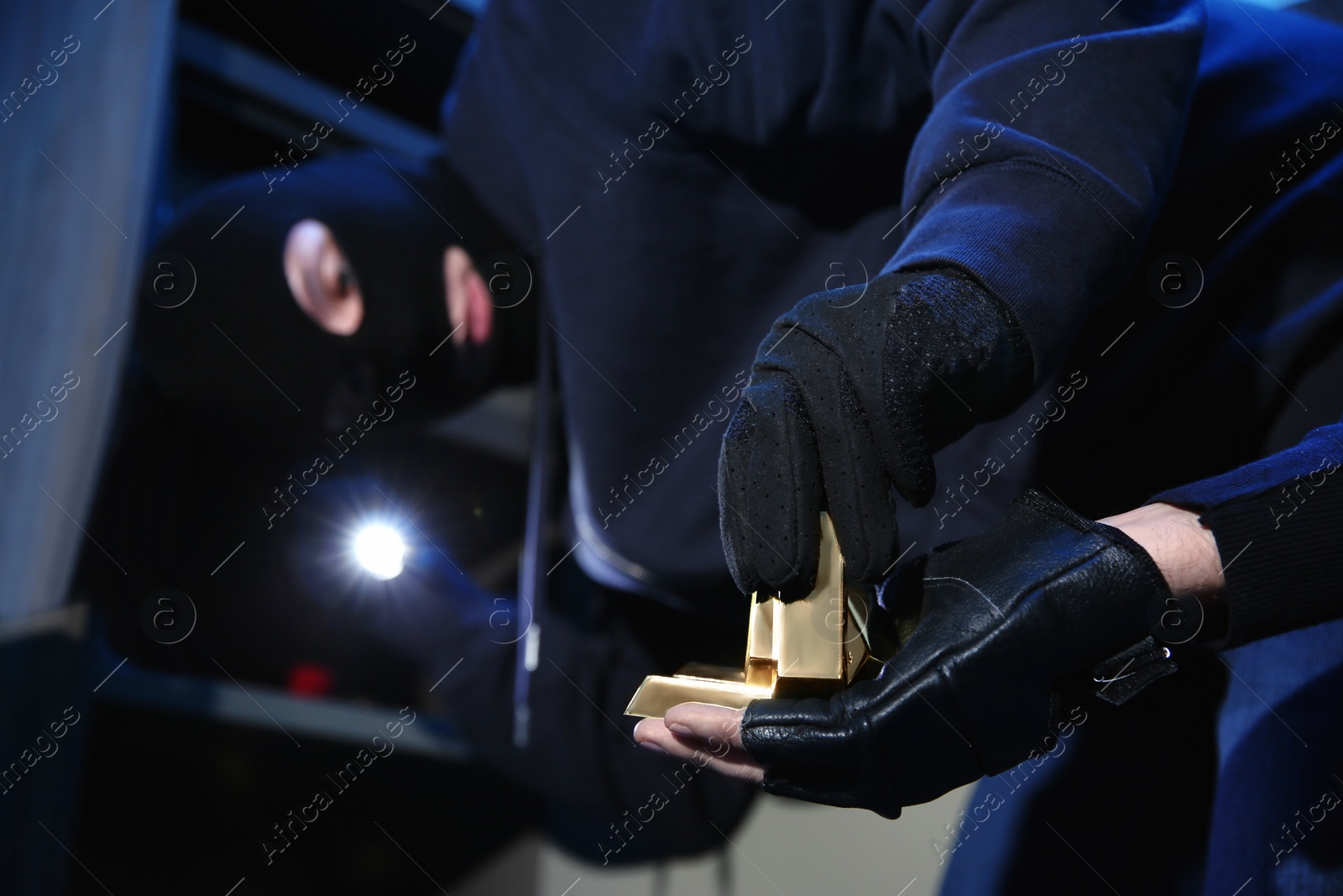 Photo of Thieves taking gold bars out of steel safe indoors at night