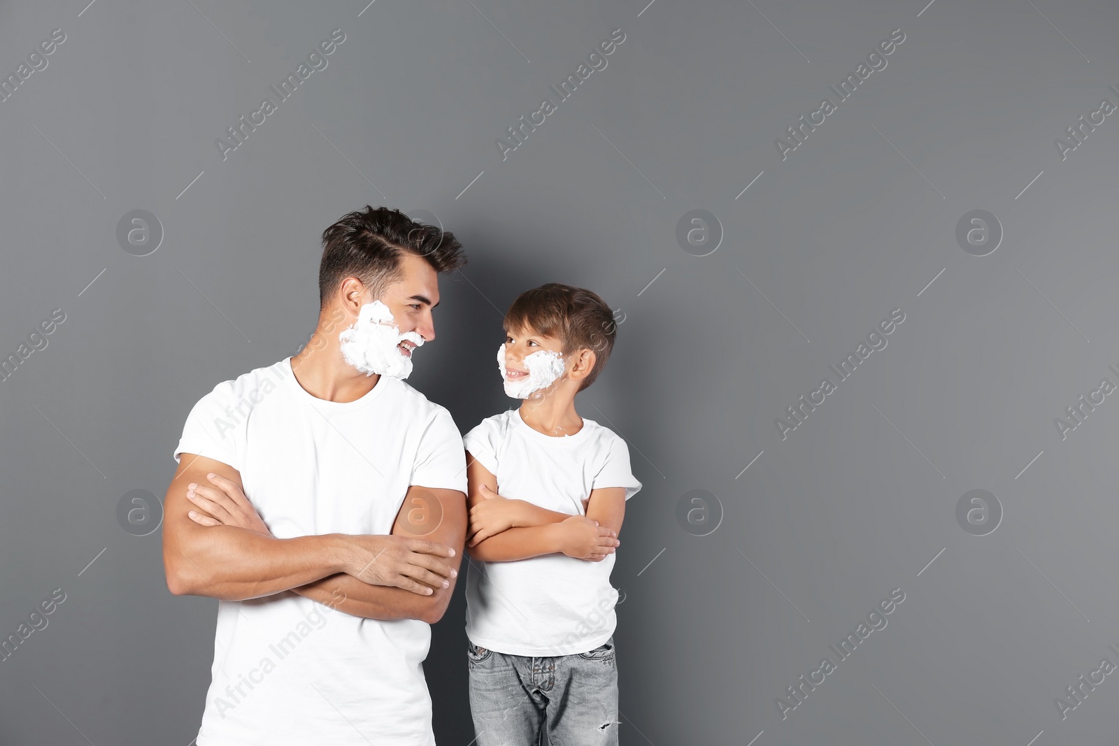 Photo of Father and son with shaving foam on faces against color background. Space for text