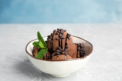 Photo of Bowl of chocolate ice cream and mint on grey table, space for text