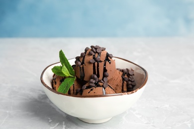 Bowl of chocolate ice cream and mint on grey table, space for text