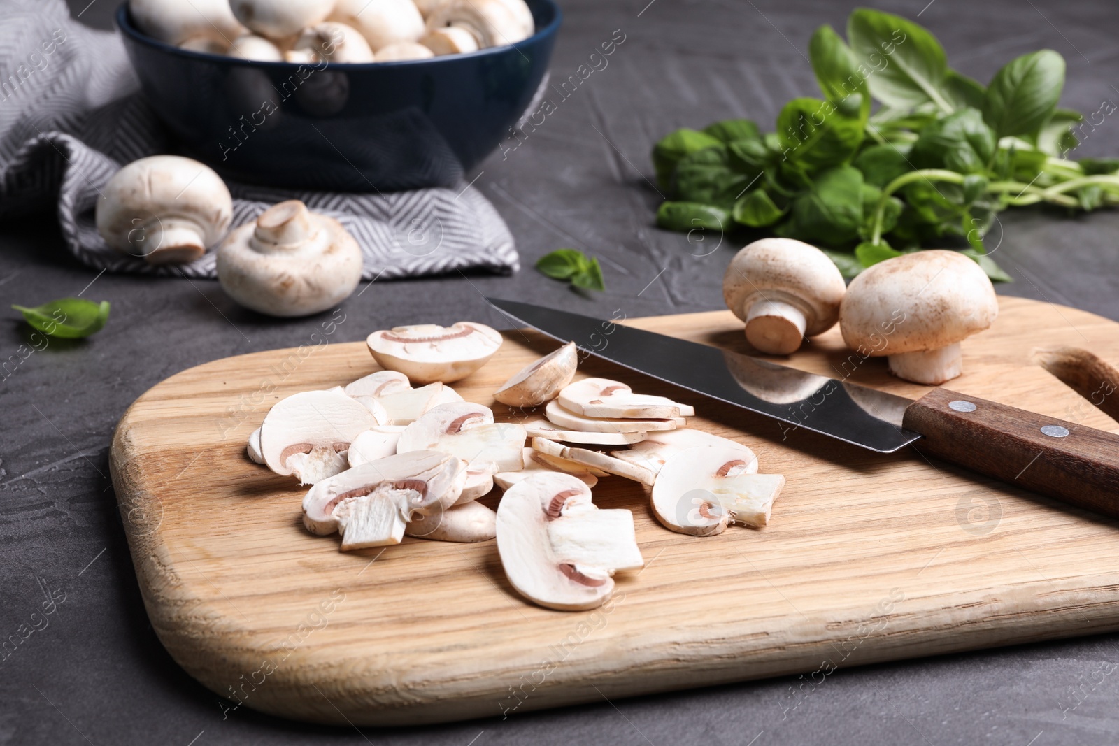 Photo of Wooden board with sliced raw mushrooms on table