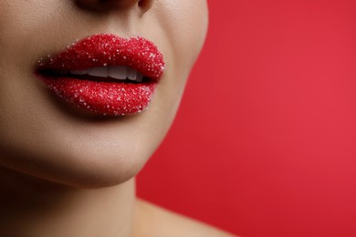Closeup view of woman with lips covered in sugar on red background. Space for text