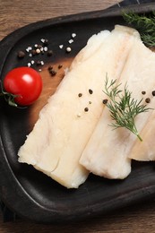 Raw cod fish, dill, tomatoes and spices on wooden table, top view