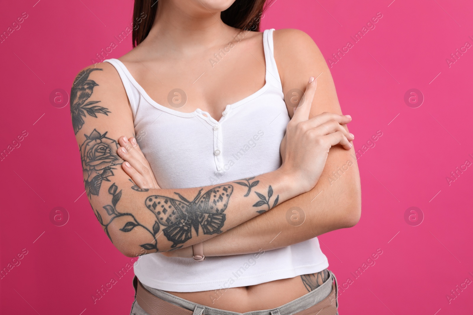 Photo of Woman with tattoos on body against pink background, closeup