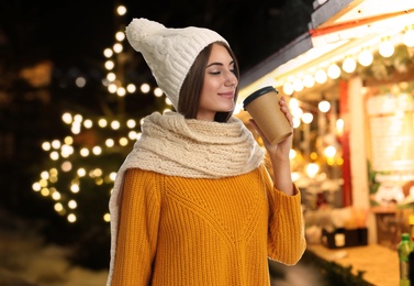 Image of Happy beautiful woman with paper cup of mulled wine at Christmas fair