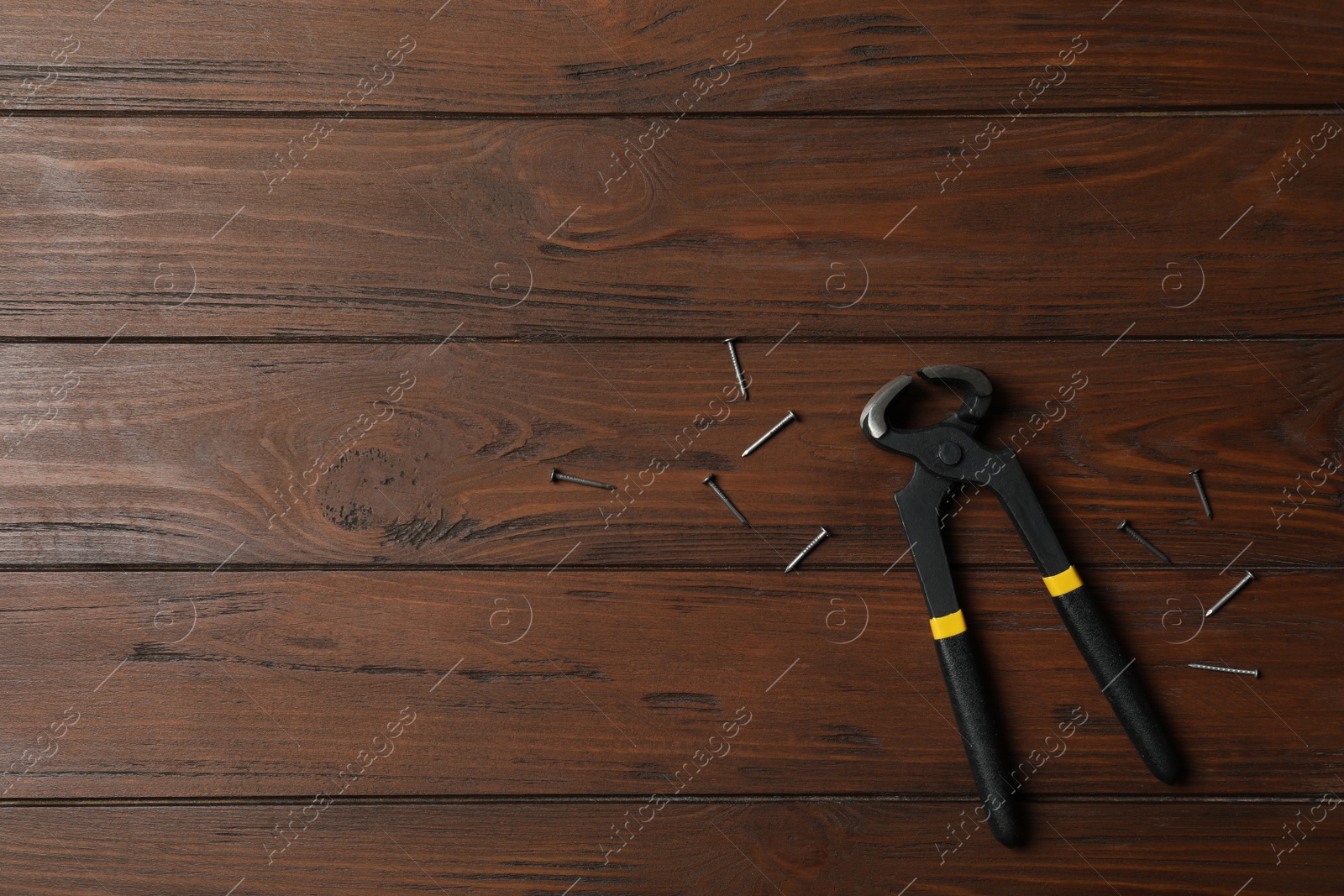 Photo of Pincers and nails on wooden background, flat lay with space for text. Carpenter's tool