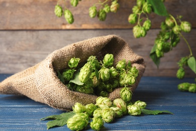Sackcloth bag with fresh green hops on wooden table. Beer production
