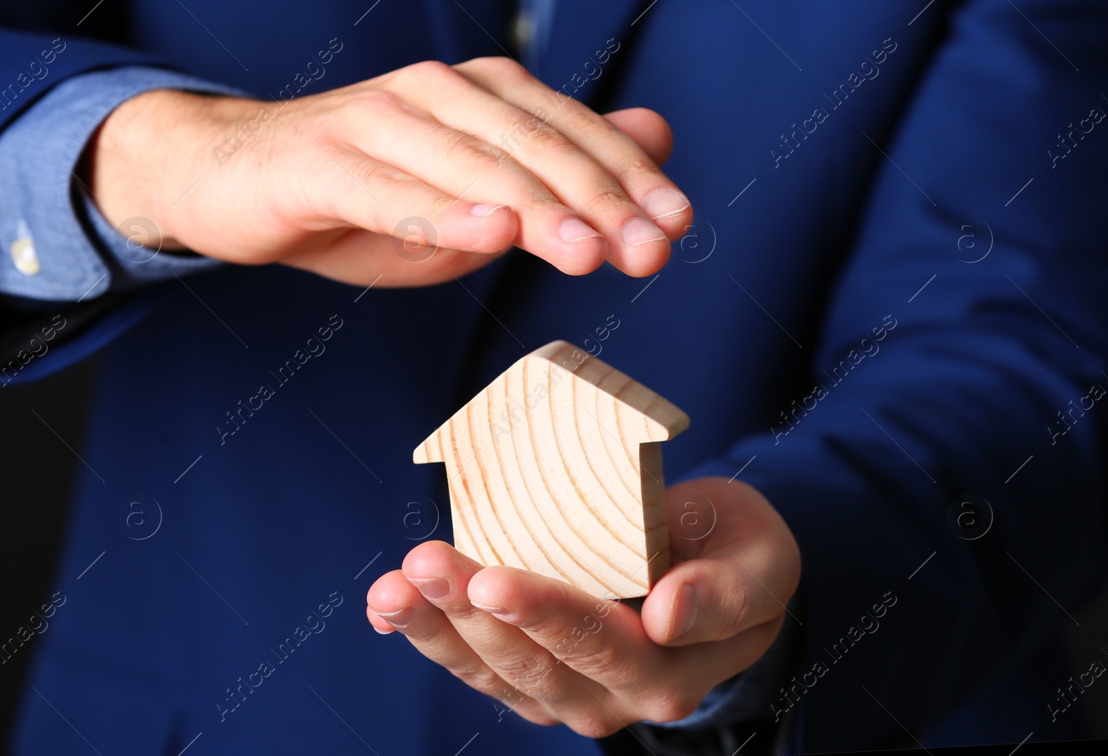 Photo of Male agent covering wooden house, closeup. Home insurance