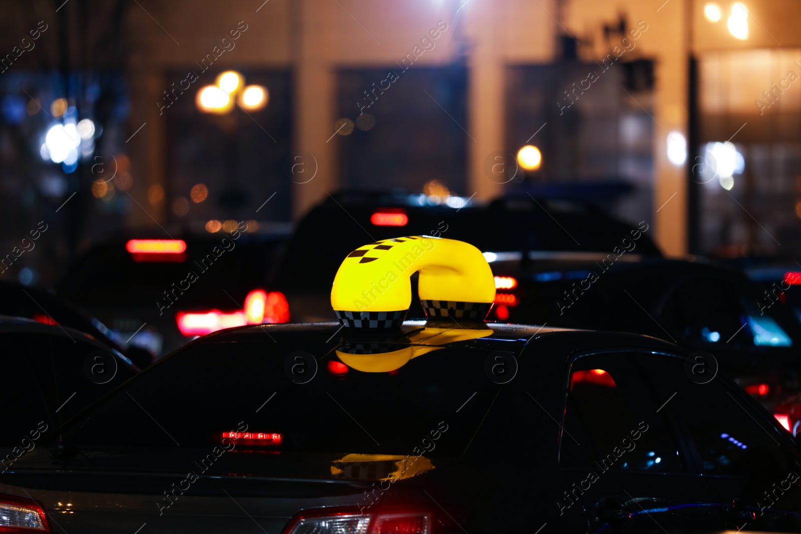 Photo of Taxi car with yellow checkered sign on city street in evening
