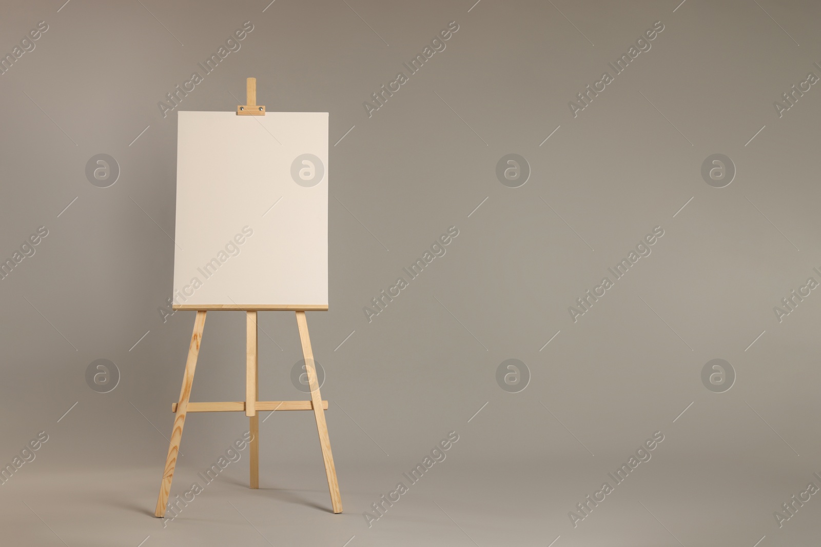 Photo of Wooden easel with blank canvas on grey background. Space for text