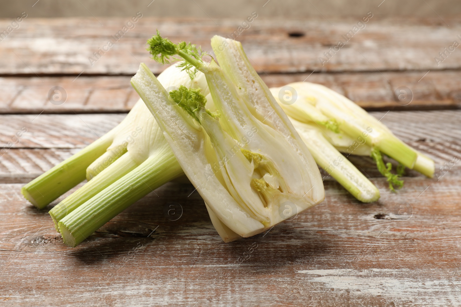 Photo of Whole and cut fennel bulbs on wooden table, closeup