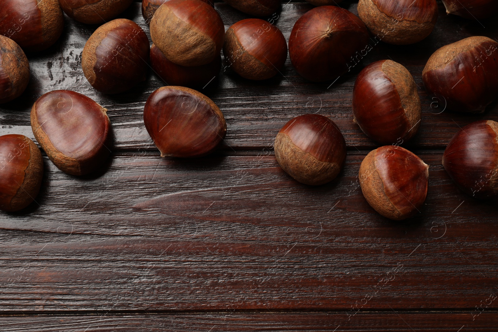 Photo of Sweet fresh edible chestnuts on wooden table, top view. Space for text