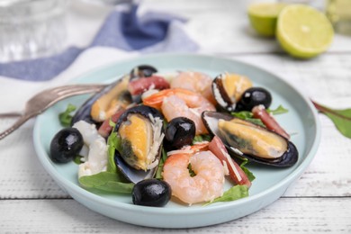 Plate of delicious salad with seafood on white wooden table