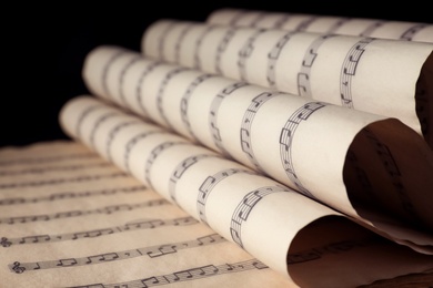 Photo of Old wrapped sheets with music notes on black background, closeup