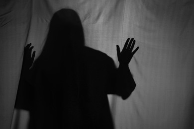 Silhouette of creepy ghost behind grey cloth