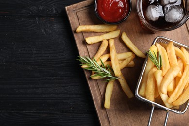 Tasty french fries, ketchup and soda drink on dark wooden table, top view. Space for text