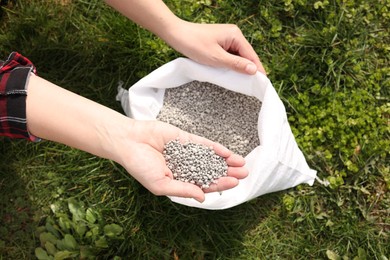 Photo of Woman with fertilizer on green grass outdoors, top view