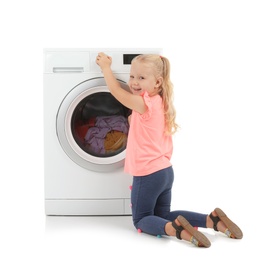 Photo of Cute little girl turning on washing machine with laundry on white background