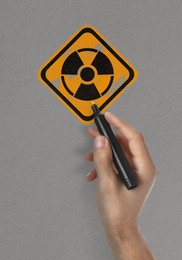 Image of Man painting radiation warning symbol with marker on light grey surface, closeup