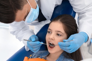 Professional dentist working with little girl in clinic