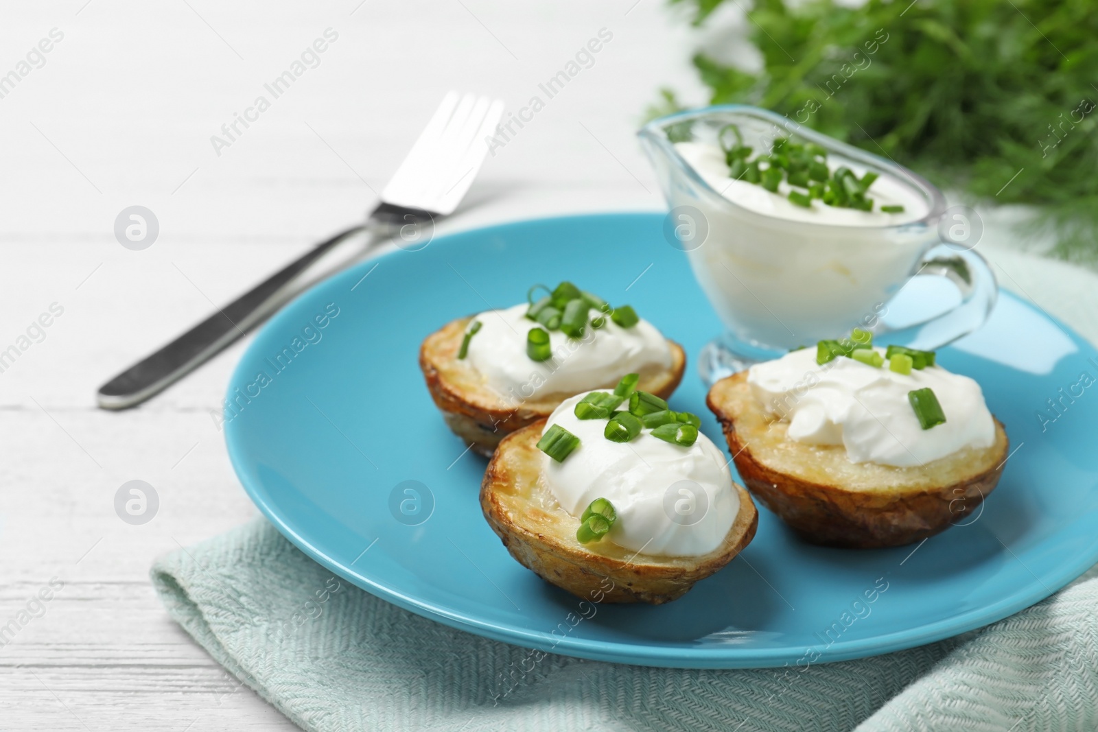 Photo of Delicious potato wedges with sour cream on white wooden table