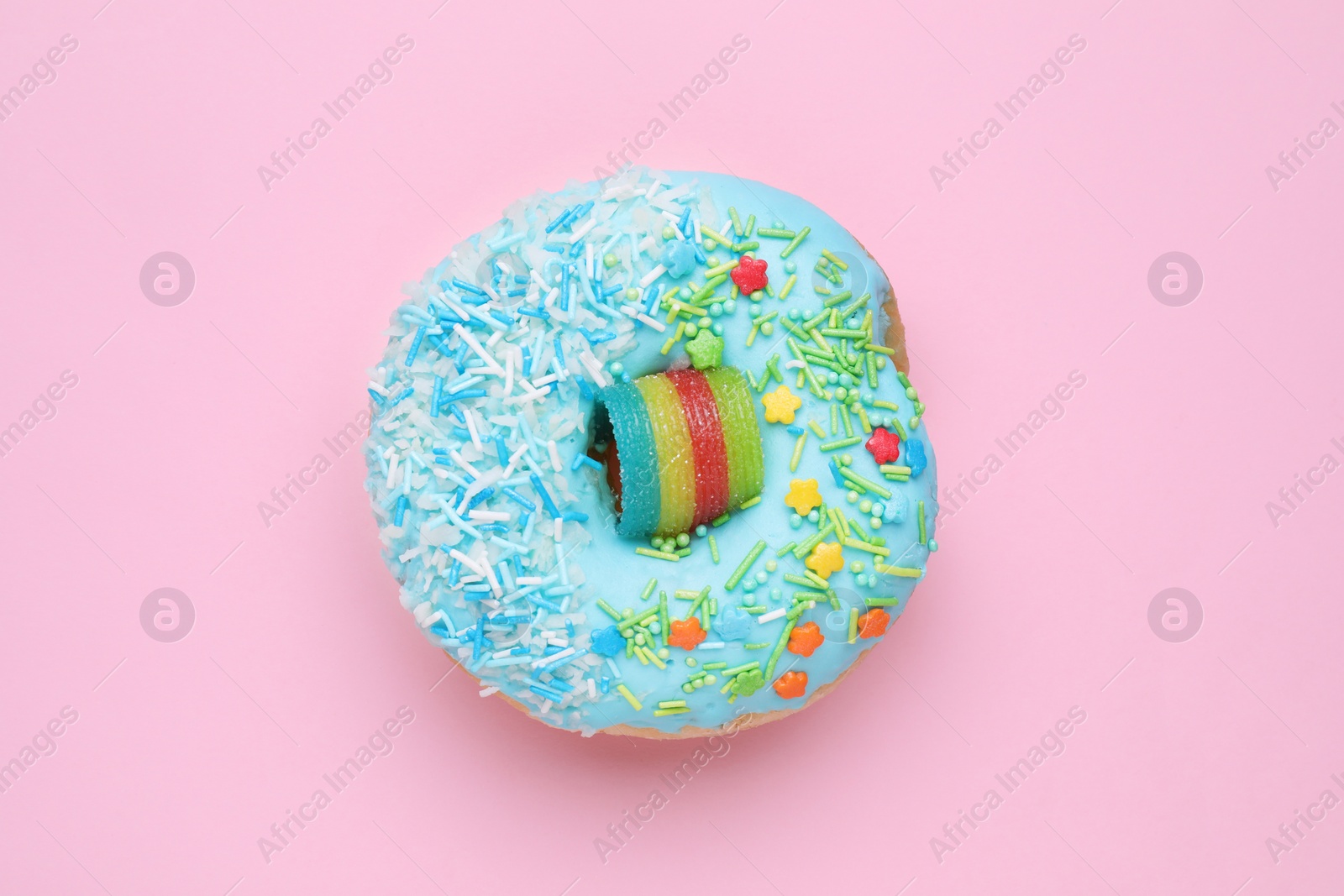 Photo of Glazed donut decorated with sprinkles on pink background, top view. Tasty confectionery