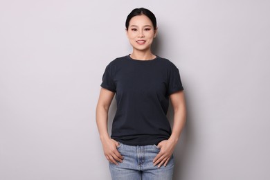 Woman wearing black t-shirt on light grey background