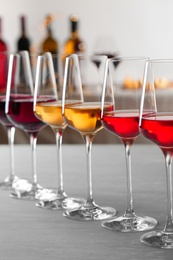 Row of glasses with different wines on table against blurred background