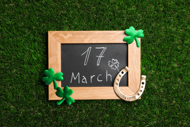 Flat lay composition with horseshoe and chalkboard on grass. St. Patrick's Day celebration