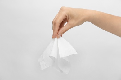 Photo of Woman holding paper tissue on light background, closeup