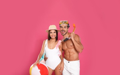 Photo of Young attractive couple in beachwear with snorkel and ball on pink background