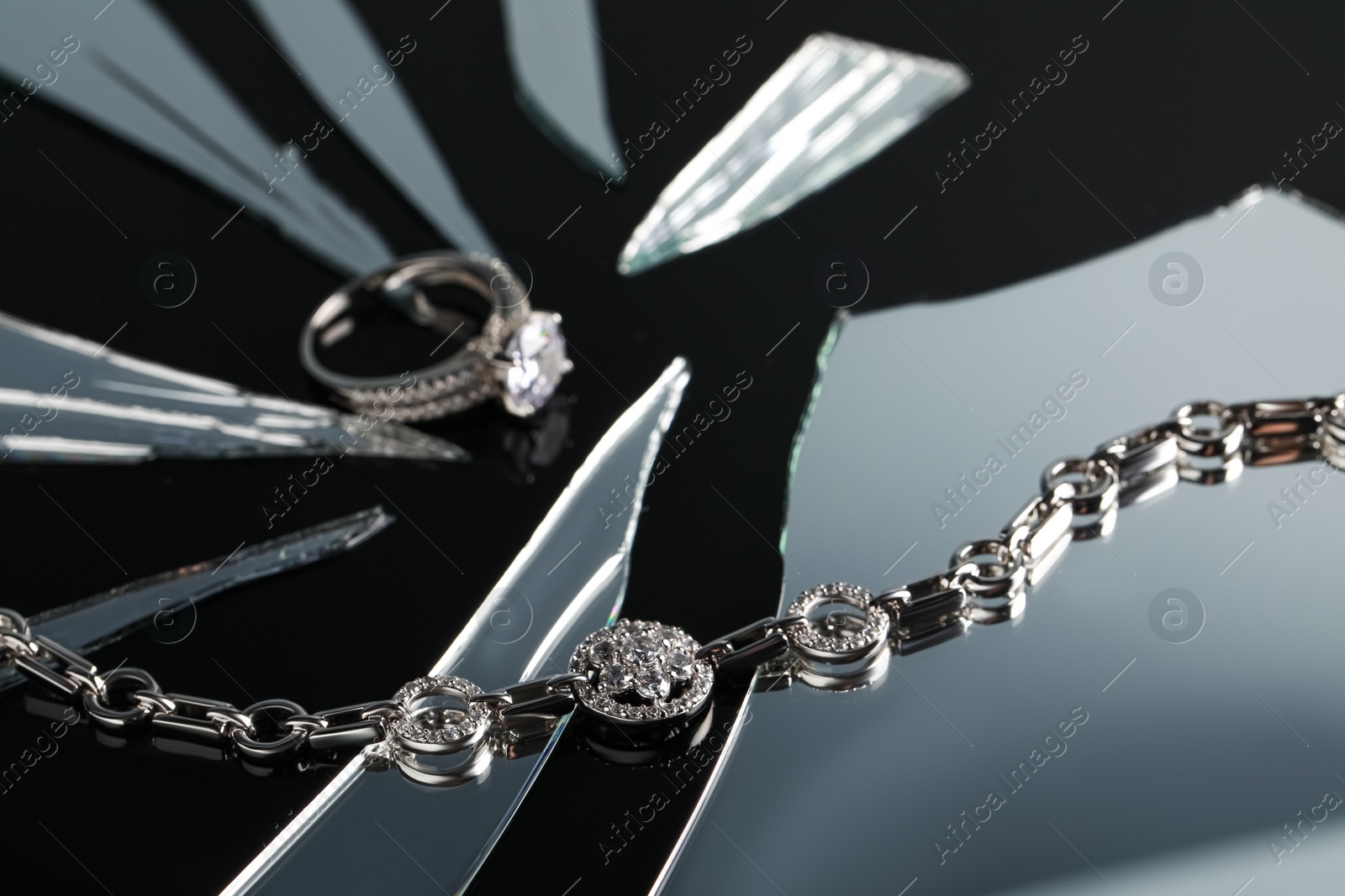 Photo of Luxury jewelry. Stylish presentation of elegant ring and bracelet on black mirror surface with broken glass