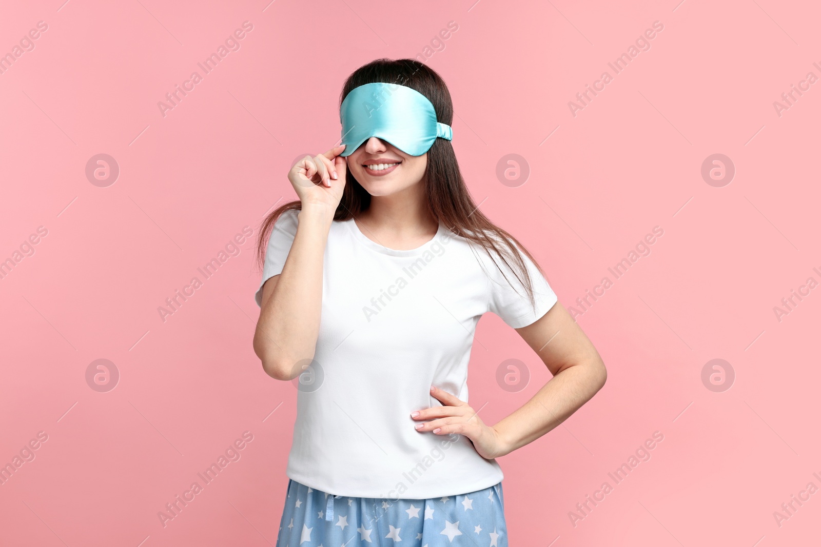 Photo of Happy woman in pyjama and sleep mask on pink background