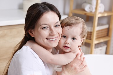 Mother bathing her cute little baby in tub at home