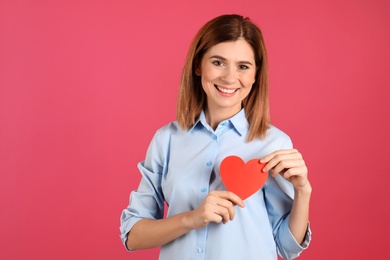 Photo of Portrait of woman with paper heart on color background. Space for text