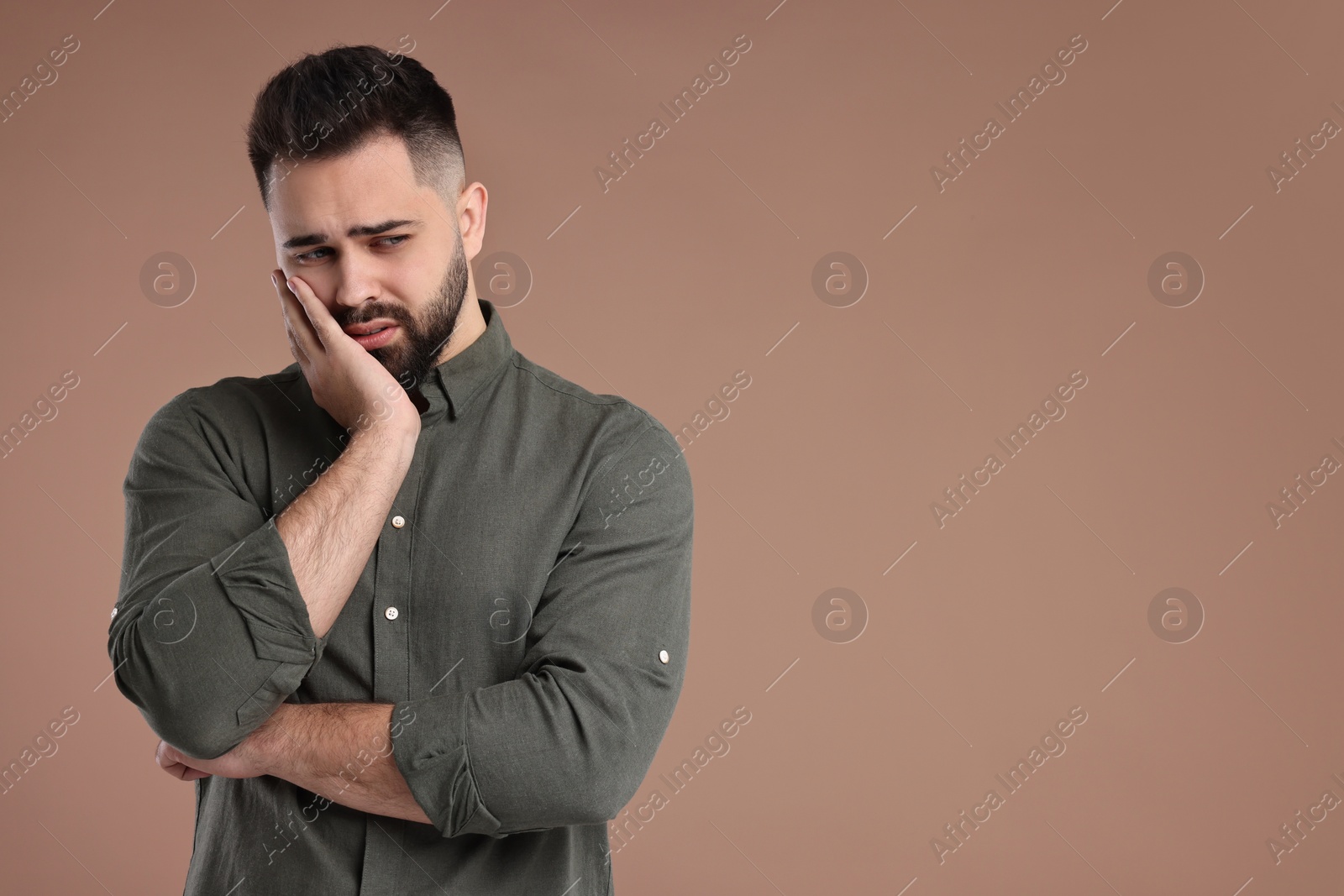 Photo of Portrait of sad man on brown background, space for text