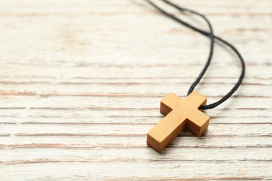 Photo of Christian cross on white wooden table, closeup. Space for text