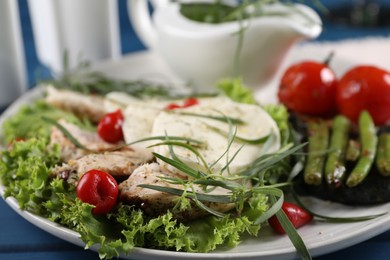 Photo of Tasty mozzarella, chicken and vegetables with tarragon on table, closeup