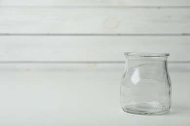 Photo of Empty glass jar on white table, space for text