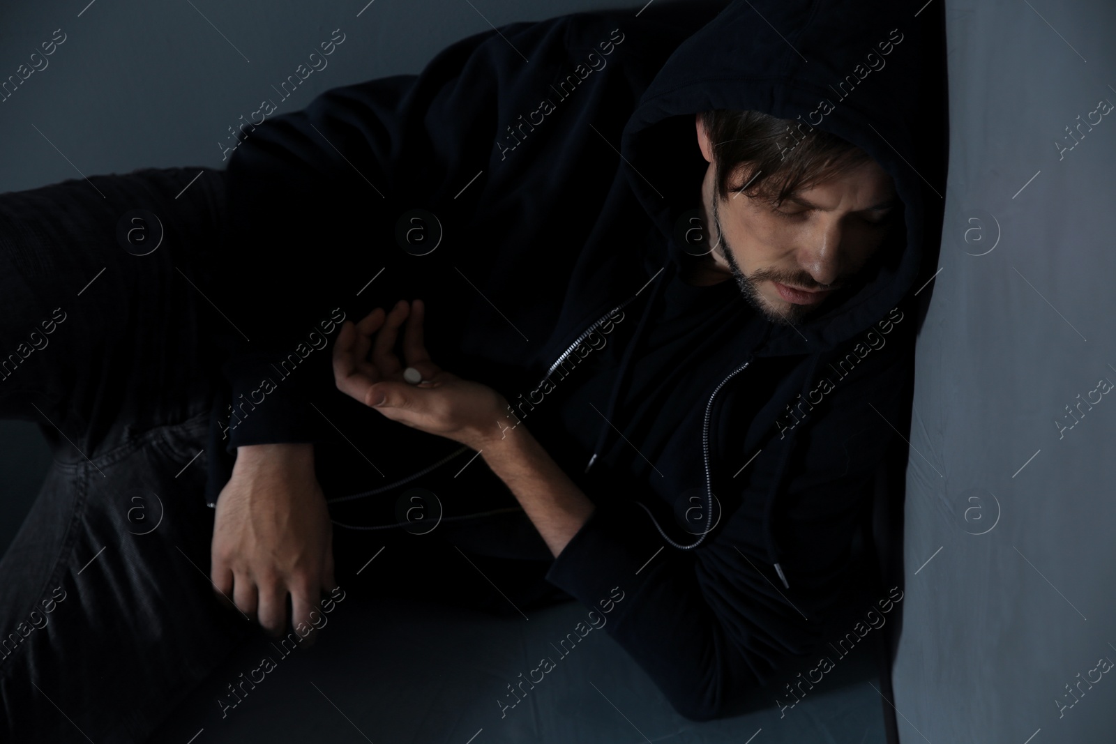 Photo of Passed out junkie after using drugs near grey wall