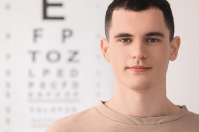 Portrait of young man against vision test chart
