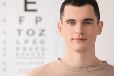 Photo of Portrait of young man against vision test chart