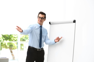 Professional business trainer near flip chart in office