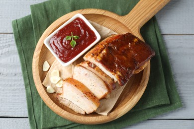 Photo of Pieces of baked pork belly served with sauce on grey wooden table, top view