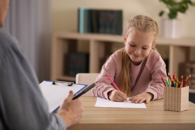 Photo of Little girl on appointment with child psychotherapist indoors